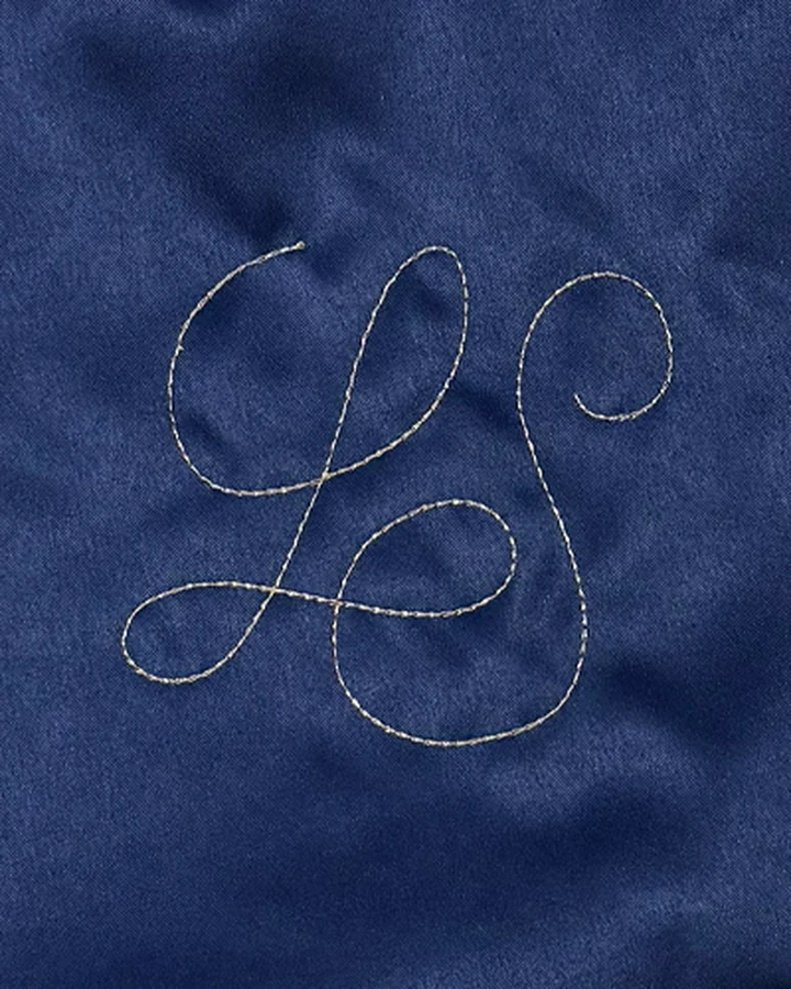 LS monogram embroidered in calligraphy on the navy satin of a Knot Bag