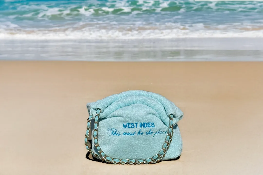 Turquoise terry Balagan embroidered “West Indies, This must be the place”, resting on the sand