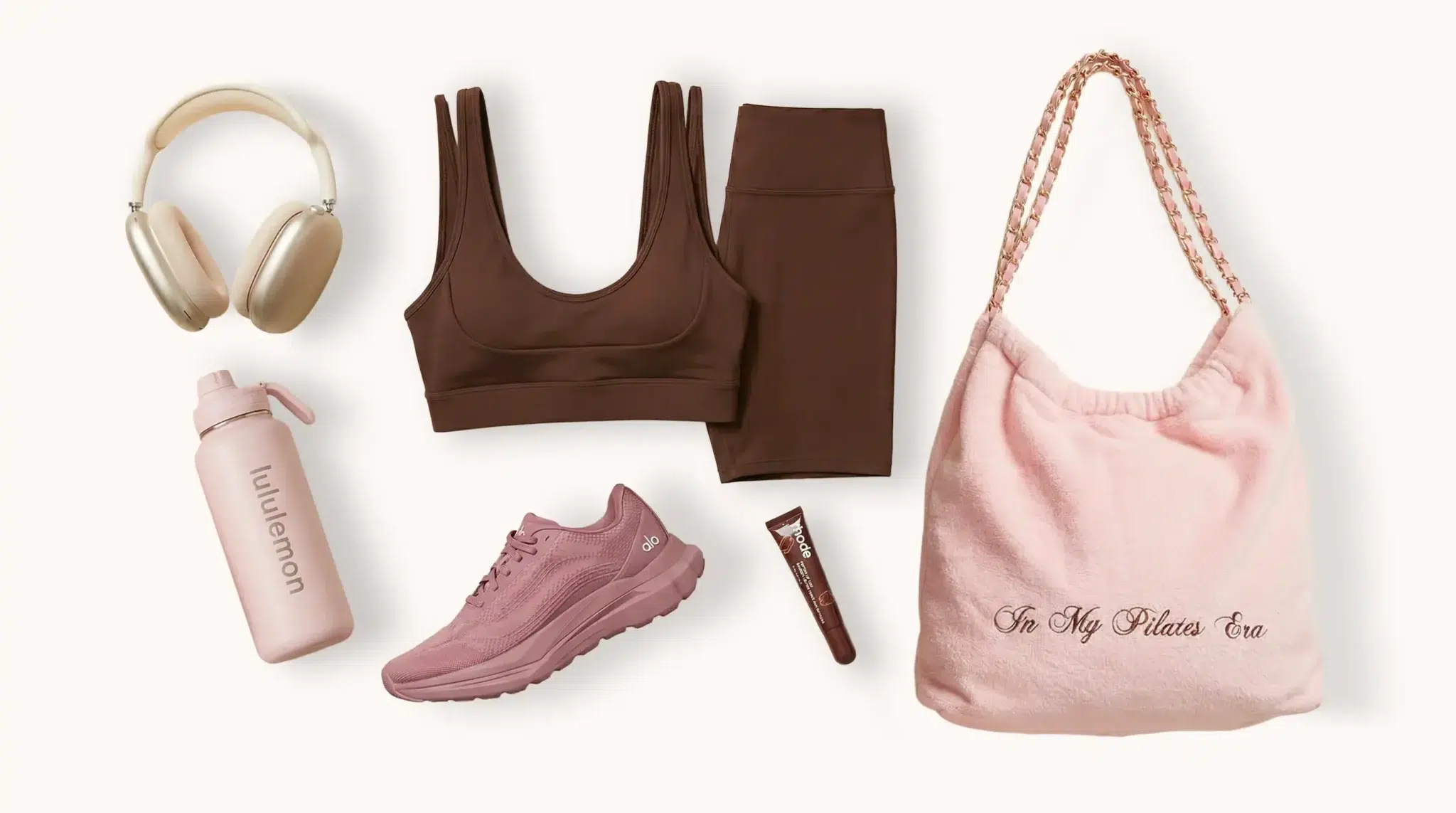 flat lay photo tenue de yoga skims x nike , alo sneakers, lululemon gourde, rhode lip tint, sac en éponge rose brodé