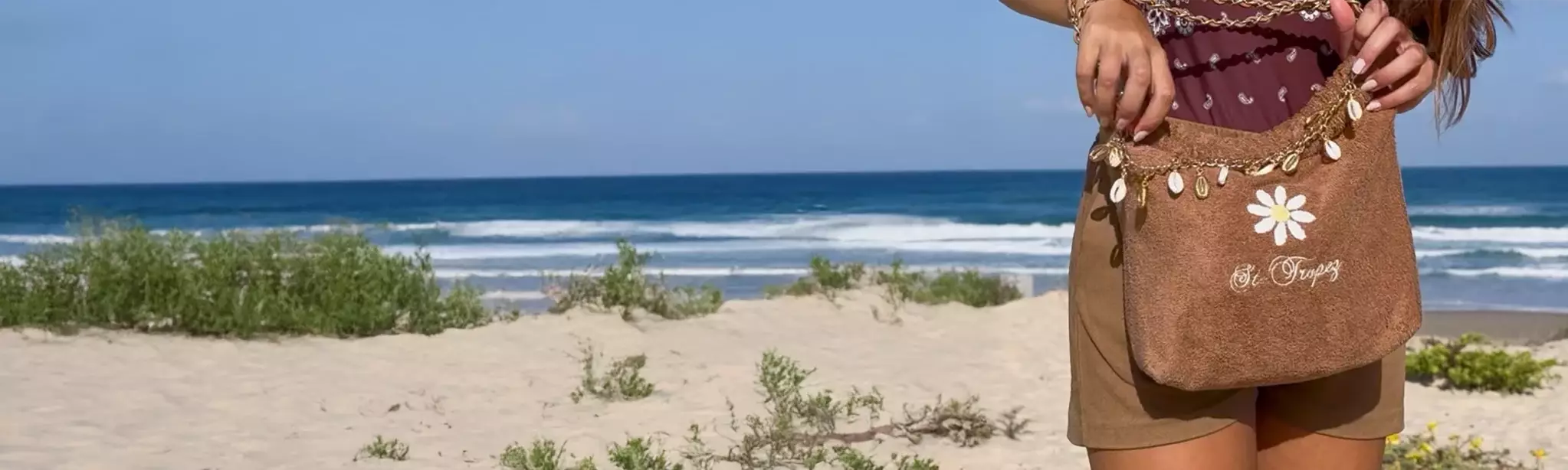 LESLIE-SULMAN-BIJOUX-DE-SAC-shell-out-lkbk-10-3-gold-cowrie Chaine de sac composée de coquillages cowries naturels et dorés accroché à un sac balagan de la collection beach&beyond Leslie Sulman