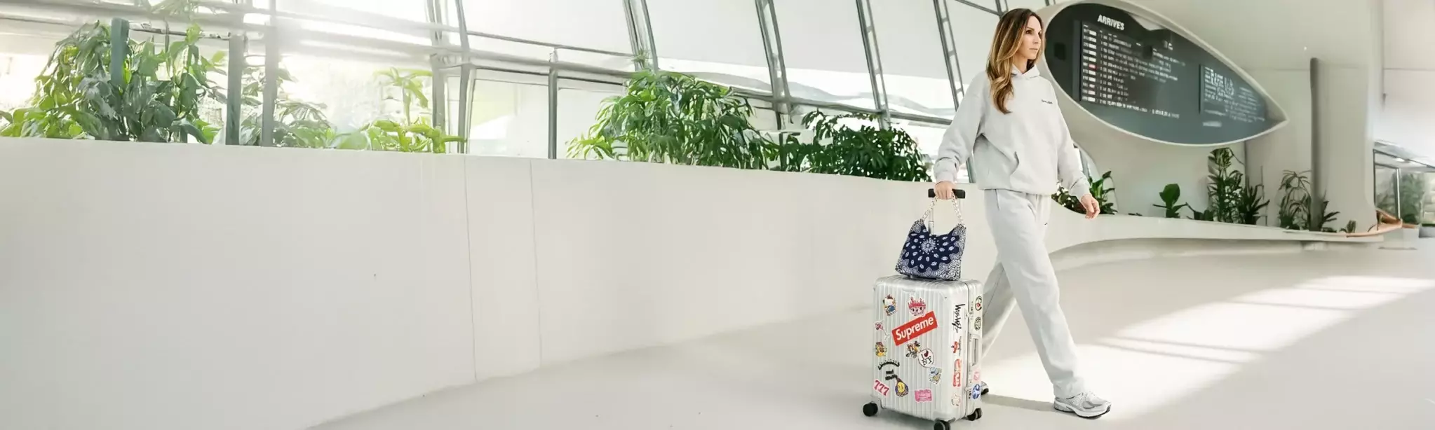 Leslie-Sulman-Balagan-Bandana-bag-navy-lookbook-2-sac-voyage Influeneuse mode portant un sac bandana de la marque Leslie Sulman dans le hall d'un aeroport. Posé sur sa valise rimowa