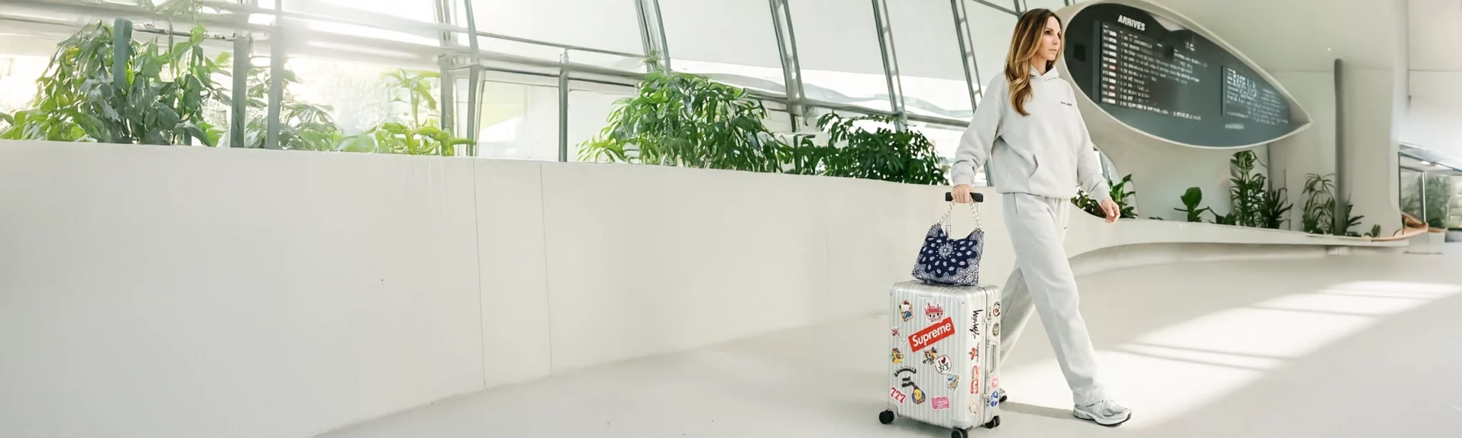 Leslie-Sulman-Balagan-Bandana-bag-navy-lookbook-2-sac-voyage Influeneuse mode portant un sac bandana de la marque Leslie Sulman dans le hall d'un aeroport. Posé sur sa valise rimowa